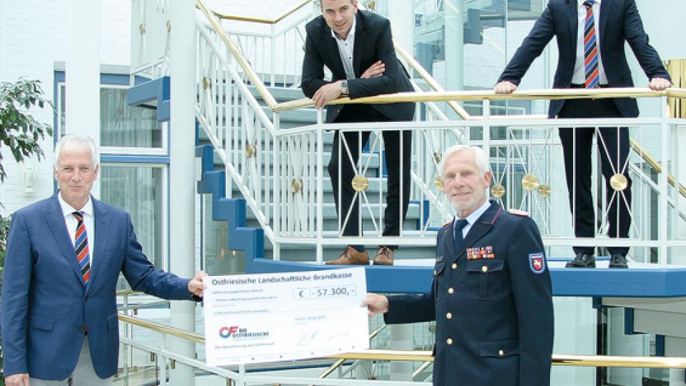Thomas Weiss, Gerrit Wilken und Tammo Keck (von links) bedanken sich bei Ernst Hemmen (unten rechts stehend), stellvertretend für alle ostfriesischen Feuerwehren, für die in 2020 geleisteten Einsätze.  © Foto: Brandkasse