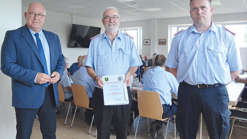 Freut sich über seinen Ehrentitel: Friedrich Schmidt (Mitte), dem Bürgermeister Hans-Peter Heikens (links) gerade seine Ernennungsurkunde überreicht hat. Rechts im Bild der amtierende Gemeindebrandmeister Jan Remmers.  © Foto: Hoegen