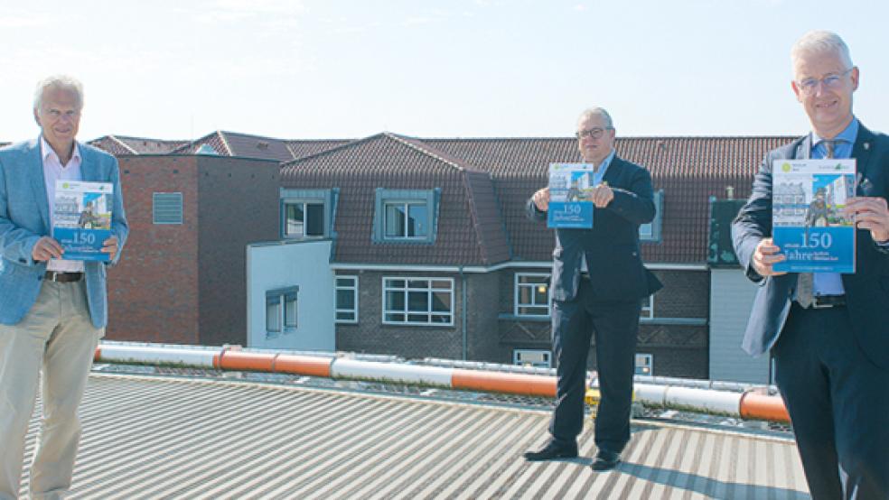 Dr. Hans-Jürgen Wietoska, Geschäftsführer Holger Glienke und Landrat Matthias Groote stellten die Festschrift zum 150-jährigen Jubiläum des Klinikums Leer vor. Im Hintergrund ist der Bau von 1927 zu sehen.  © Fotos: Berents (1)/Klinikum (1)