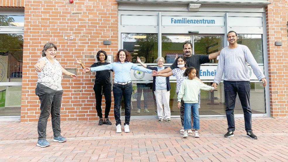 Mit offenen Armen vor der neuen »Heimat« des Gesprächskreises »Offene Arme«: (von links) Birgit Zeunert, Lorene Bona, Naima Michel, Monika Kuhl, Abdul Kareem Abdullah Safer mit Tochter Julia sowie Diaaelrahman Ohamed Osman Ali Osman mit Tochter Alyaa. Kleines Bild: Das neue Logo.  © Foto: privat
