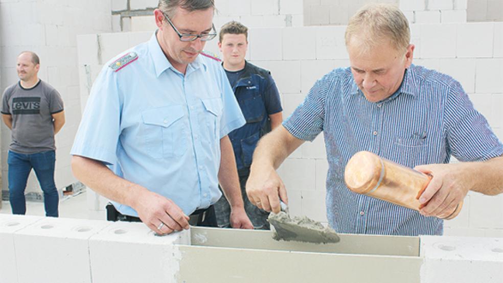 Bundes Ortsbrandmeister Hans-Hermann Leemhuis mauerte zusammen mit Bürgermeister Gerald Sap die Zeitkapsel mit einer aktuellen Zeitung, Bauplänen und etwas Kleingeld ein.  © Foto: Berents
