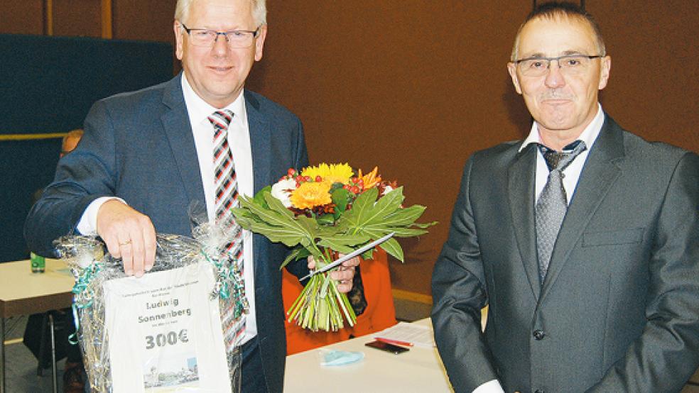 Bürgermeister Ludwig Sonnenberg (links) bekam zum Abschied aus dem Amt im Namen des Stadtrates durch den Ratsvorsitzenden Garrelt Janssen ein »Flachgeschenk« in Form eines Gutscheins und einen Blumenstrauß überreicht.  © Foto: Hoegen