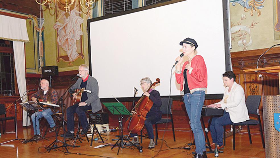 Annie Heger (mit roter Jacke) und Jan Cornelius (2. von links) mit seiner Band führten durch den Abend im Rathaussaal.  © Foto: Eden