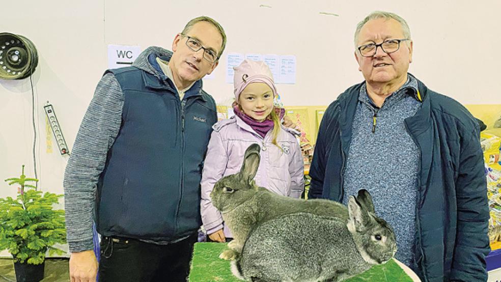 Zu den Gewinnern eines »großen Preises« anlässlich der Kreisverbandsschau gehören Wilhelm Loger (rechts) aus Möhlenwarf mit einem »vorzüglichen« Rammler der Rasse Kleinchinchilla (vorne) und Maya Goemann aus Holthusen mit einem »hervorragenden« Blaugrauen Wiener. Mit auf dem Foto ist Vereinsvorsitzender und Ausstellungsleiter Michael Goemann aus Holthusen.  © Foto: Kuper