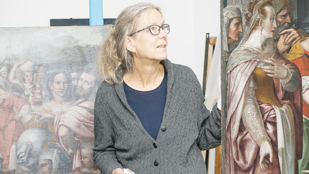 Die Bilder in Nahsicht und dazwischen die Kuratorin Dr. Annette Kanzenbach, links hinter ihr ist das Selbstbildnis des Malers zu sehen.  © Foto: Martinus Ekkenga 