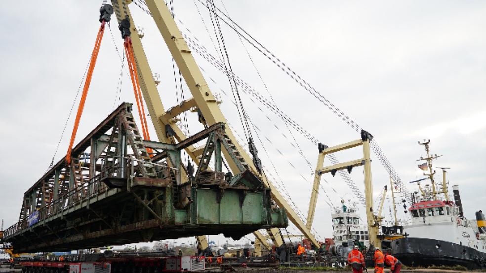 Nach der Ankunft bei der EFG Port Papenburg hob Schwimmkran »Enak« das Überbau-Element der alten Friesenbrücke am Mittwochmittag auf zwei jeweils 16 Meter lange Spezialtrailer. Diese brachten das Segment auf ihren insgesamt 20 Achsen zu einer eigens dafür vorbereiteten Fläche auf dem Terminal-Gelände. Dort wird es nun für die weitere Verwertung zerlegt. © Foto: EMS Fehn Group