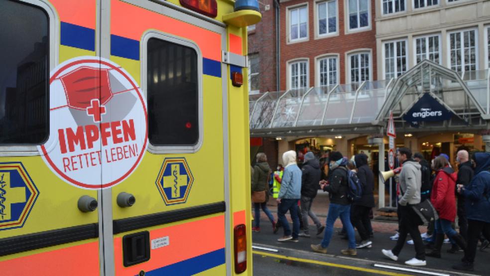 Gegensätze in Emden: An einem Rettungswagen mit Werbung für das Impfen ziehen Impfgegner vorbei. © Foto: Recke