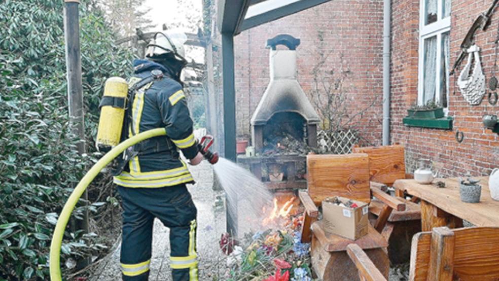 Mit einem Strahlrohr löscht ein Feuerwehrmann unter Atemschutz den brennden Abfall.  © Foto: Bruins