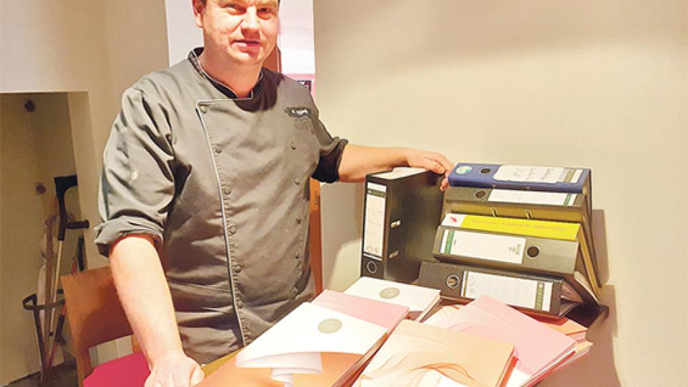 Markus Leggedör mit einigen seiner Unterlagen. Die Kalenderbücher im Vordergrund beinhalten die Dokumentation der Reinigungspläne und der Temperaturregulierung aus 2021.  © Foto: Berents