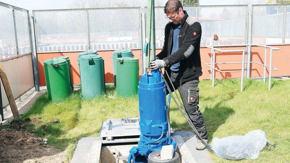 Die neue Pumpe hängt am Kran, den Klärwerks-Mitarbeiter Johannes Luikenga bedient. Schwimmmeister Markus Bakker bugsiert die Pumpe in den Schachteingang.  © Foto: Hoegen