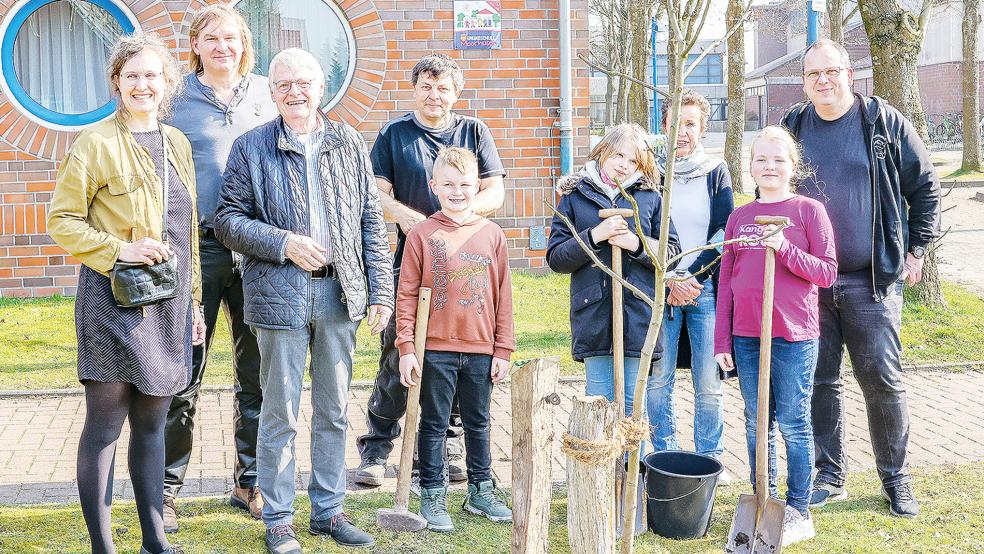 Sie hatten ihren Spaß bei der 100. Apfelbaum-Pflanzung auf dem Gelände der Grundschule Moorhusen: Im Bild von links Christine Strauß (Ostfrieslands Streuobstwiesen), Matthias Bergmann und Elko Berents (Irma-Waalkes-Stiftung), Hausmeister Theo Brungers, Klassenlehrerin Birgit Valais, Rektor Ulrich Kramer sowie Lia, Sophie und Tammo.  © Foto: privat