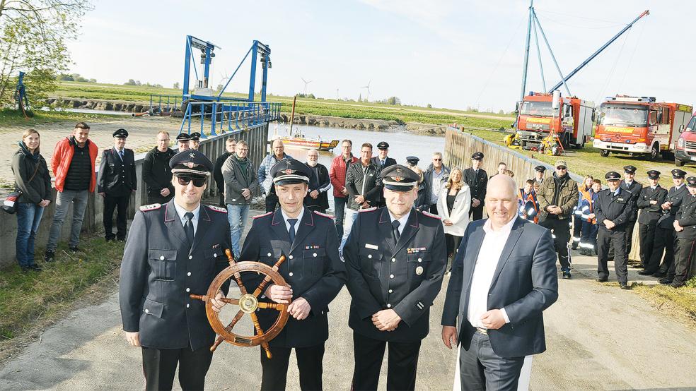 Zur Übergabe des Bootes, im Hintergrund, bekam die Feuerwehr Bingum ein Steuerrad, dass der stellvertretende Ortsbrandmeister Jann Freese (links) und Ortsbrandmeister Ralf-Dieter Harbers festhalten. Daneben der stellvertretende Stadtbrandmeister Jens Winkelmann und Bürgermeister Claus-Peter Horst.  © Foto: Wolters