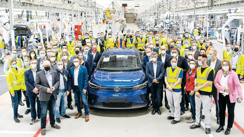 Mitarbeiter von VW Emden stehen neben einem der ersten in der neuen Produktionshalle produzierten ID.4.  © Foto:dpa / Sina Schuldt