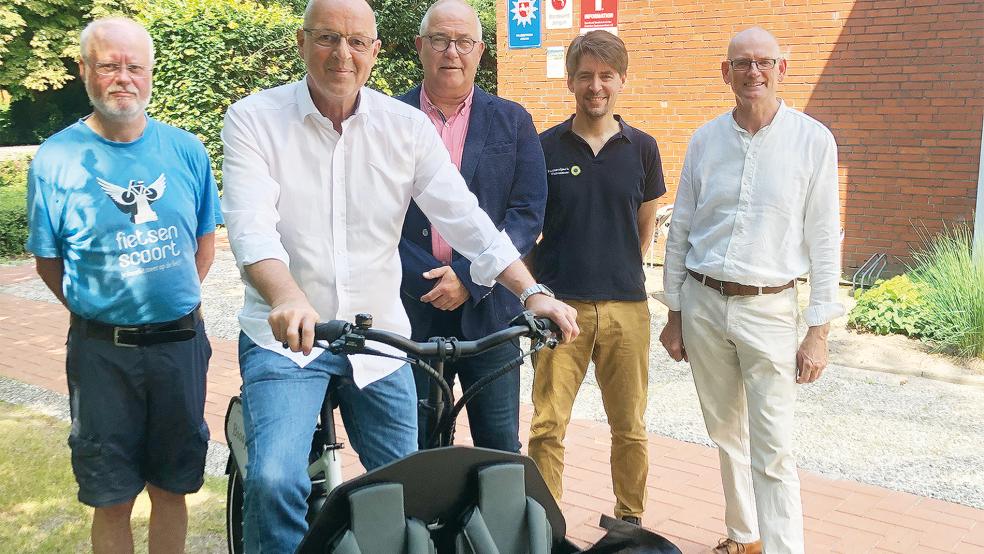 Bürgermeister Hans-Peter Heikens (Mitte) nahm das Lastenrad von Jürgen Rahmel (sitzend) und Jan Wagner (Vierter von links) von der Biosphärenregion Niedersächsisches Wattenmeer entgegen. Wolfgang Aehle (links) und Anton Scholtalbers (rechts) vom Verein »OstfriesenFiets« unterstützen das Projekt.  © Foto: Busemann