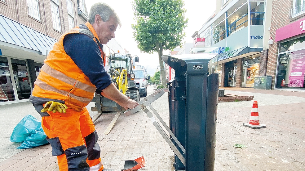 Ein Mitarbeiter der Stadtwerke montiert einen der neuen Mülleimer in der Fußgängerzone von Leer.  © Foto: Stadtwerke
