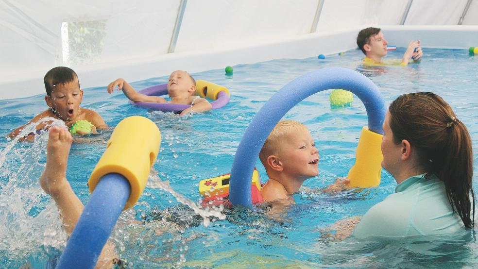 Die Holthuser Kindergartenkinder toben und plantschen im mobilen Schwimmbecken. Selina Feindt (vorne rechts) und Niklas Knoll (Hintergrund) vom DLRG-Landesverband Niedersachsen helfen ihnen dabei, sich an das Wasser zu gewöhnen.  © Fotos: Busemann