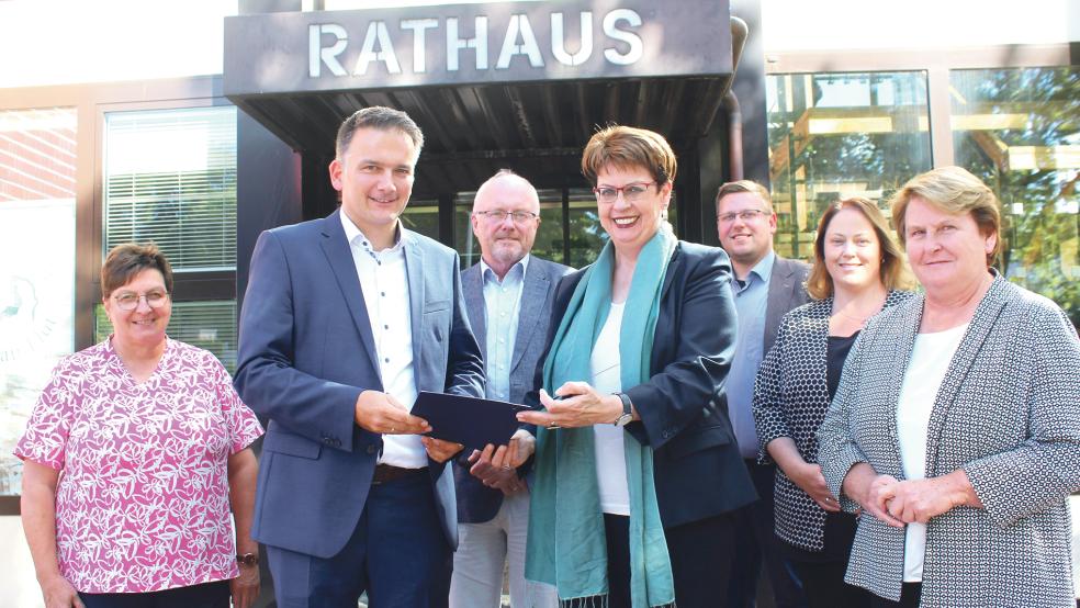 Die Europa- und Regionalministerin Birgit Honé (Mitte) überreicht Bundes Bürgermeister Uwe Sap (2. von links) den Förderbescheid vor dem Rathaus. Mehrere Fraktionsvertreter des Gemeinderates waren bei der Übergabe dabei.  © Foto: Busemann