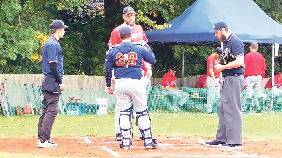 Jens Flink (in rot) bei der Plate-Conference mit Malte Grewe von den Waves (Nummer 39) und den Umpire (Schiedsrichter im Baseball).  © Foto: privat