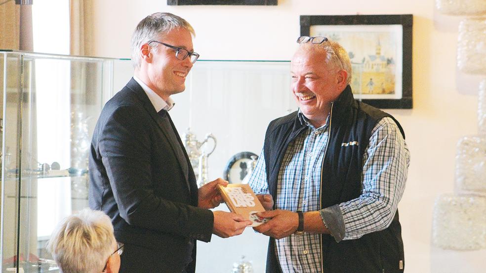 Bürgermeister Abbas überreichte Reents nach seinem Vortrag einen Fettnäpfchenführer Ostfriesland.  © Foto: Berents