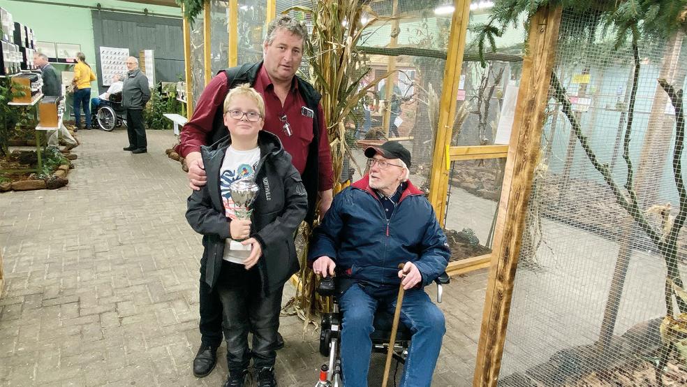 Die Jugendvoliere erhielt in diesem Jahr den Bürgermeister-Pokal der Stadt Weener. Das Foto zeigt den 82-jährigen Züchter und Ausstellungsleiter Albert Wiegmann (rechts) als ältestes und den neunjährigen Hendrik Rickling als jüngstes Mitglied sowie Torsten Rickling als Jugendwart. © Kuper