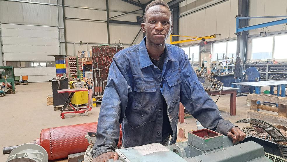 In der Produktionshalle der Seelan Elektromotoren GmbH in Weener: Für das Foto hat Abdoul Diallo nochmal eine Arbeitsjacke angezogen, doch die Ausländerbehörde hat ihm die Arbeitserlaubnis wieder entzogen. Nachdem der 20-Jährige sein Studium in der Ukraine wegen des Krieges nicht aufnehmen konnte und flüchten musste, soll er nach Guinea abgeschoben werden.  © Foto: Szyska