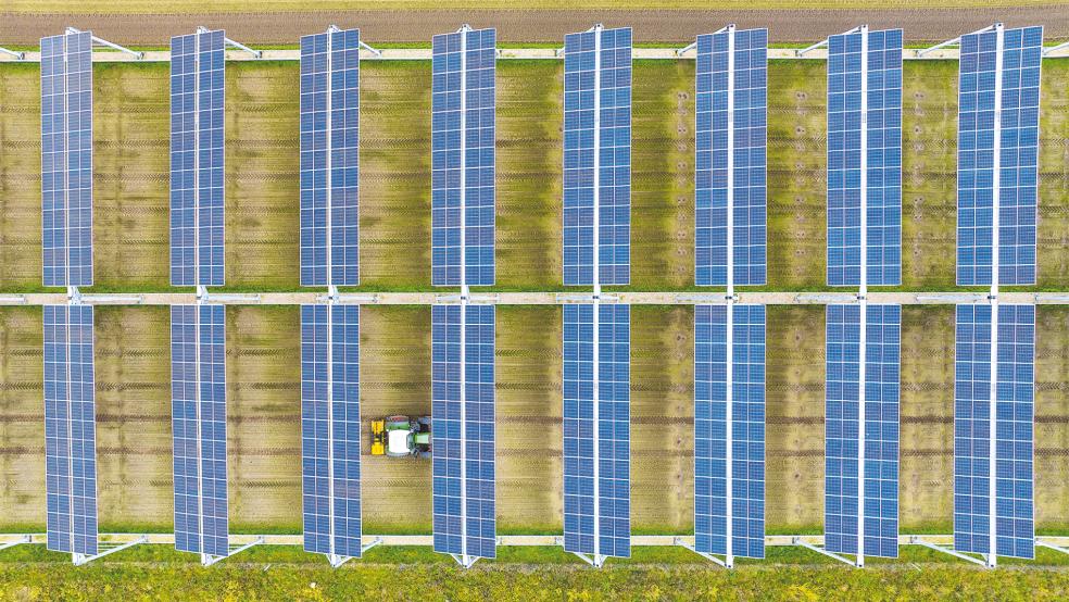 Ein Traktor fährt unter Solaranlagen hindurch. Der LHV im Landkreis Leer befürchtet durch solche Anlagen zu große Flächenverluste.  © Symbolfoto: dpa/Schulze