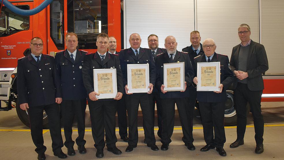 Für langjährige Mitgliedschaft geehrt wurden (mit Urkunde, von links) Detlef Boer (25 Jahre), Volker Erfkamp (40), Hinrich Wolters (50) und Ehren-Stadtbrandmeister Friedel Rügge (60 Jahre). Zu den Gratulanten gehörten (zweite Reihe, von links) Stadtbrandmeister Jörg Fisser, sein Stellvertreter Helmut Erfkamp, Ortsbrandmeister Hans-Joachim Kotulla, sein Stellvertreter Ewald Spengel, Abschnittsleiter Ernst Berends (Kreisfeuerwehr und Feuerwehrverband) und Bürgermeister Heiko Abbas.  © Foto: Kuper
