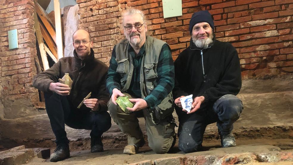 Unter dem Fundament der ehemaligen Drogerie Antoni van der Laan entdeckte Frank Meyer (rechts) viele alte Gegenstände. Grabungstechniker Axel Prussert (Mitte) dokumentiert die Funde. Hilbert Koetsier ist Eigentümer des Gebäudes und will dort unter anderem Büroräume einrichten.  © Foto: Busemann