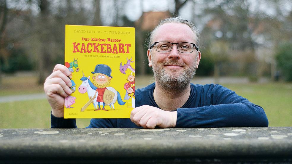 Oliver Kurth mit seinem Mutmach-Buch, das im Rotfuchs-Verlag erschienen ist. Die kleinen Bilder im Artikel zeigen seine Figuren: (von links) Ritter Kackebart mit Einhorn Windelpups, eine nicht allzu mutige Ritter-Riege und Prinzessin Tortenwerf.  © Foto: Christian Lüpke
