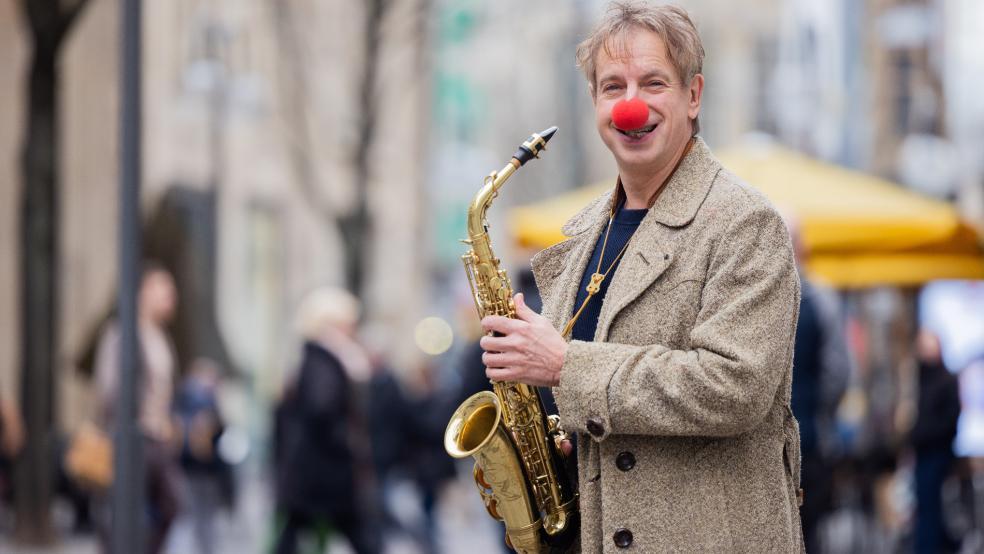 Ingolf Lück mit Saxophon und Clownsnase in der Kölner Innenstadt - mit der ostfriesischen Insel Langeoog verbindet er eine lange persönliche Geschichte. © Vennenbernd (dpa)