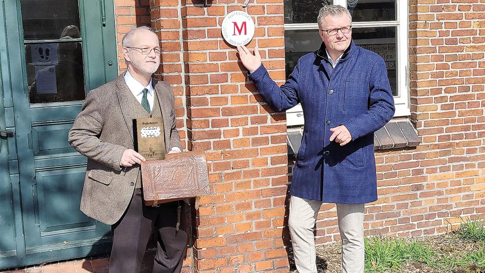 Mit Bürgermeister Theo Douwes (rechts) hat Udo Tinnemeyer die neue Plakette zur Auszeichnung inzwischen an den Eingang des Schulmuseums angeschraubt.  © Foto: privat