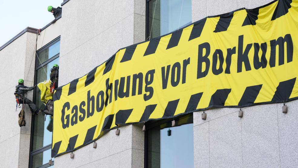 Aktivisten der Umweltschutzorganisation Greenpeace befestigen am frühen Morgen Banner an der Fassade des Landtages. Greenpeace protestiert gegen eine Gasbohrung vor der Nordseeinsel Borkum.  © Julian Stratenschulte/dpa