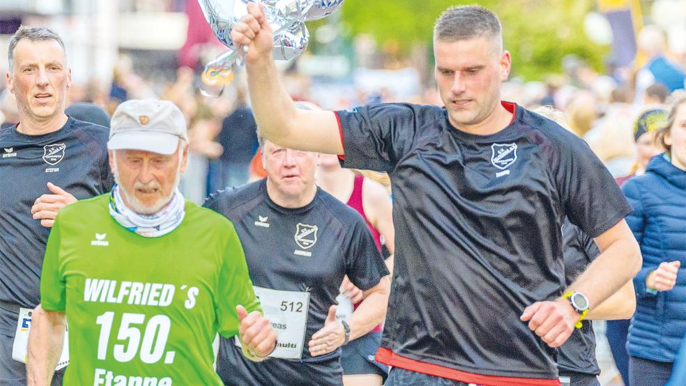 Wilfried Franzen (grünes T-Shirt) wurde von seinen Mitstreitern der Laufgemeinschaft Stapelmoorer überrascht - die letzten Meter begleiteten sie ihn in Leer ins Ziel.  © Foto: Jungeblut