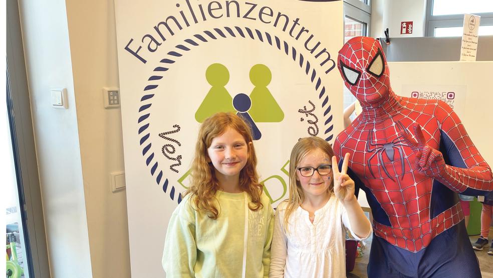 Keine Angst vor dem Spinnenmann: Emily (auf dem Foto links) und Ida stellten sich mit Spiderman vor dem Logo des Familienzentrums zum gemeinsamen Foto auf. © Kuper