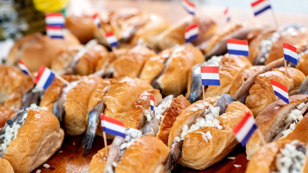 Zahlreiche Fischbrötchen mit einem Doppelmatjes und einer niederländischen Flagge liegen während der Emder Matjestage an einem Verkaufsstand. © Dittrich/dpa