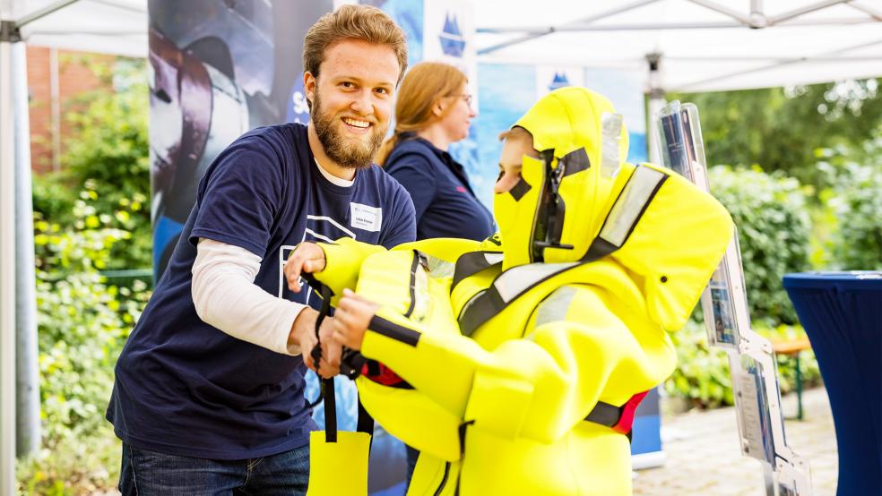 Lukas Kramer von der Mariko GmbH hilft bei der Anprobe eines Überlebensanzugs.  © Foto: Hochschule Emden/Leer