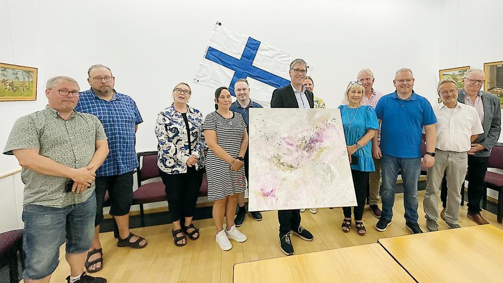 Weeners Bürgermeister Heiko Abbas (Mitte) nahm dankbar das Geschenk der finnischen Delegation aus Eurajoki um Bürgermeister Vesa Lakaniemi (Dritter von rechts) im Saal des Rathauses entgegen. Es ist ein abstraktes Gemälde des bekannten finnischen Künstlers Sanna Hakala.  © Foto: Stadt Weener
