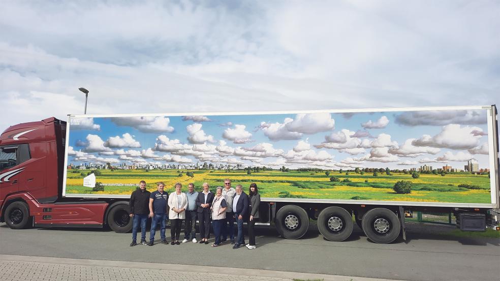 Die »Norddeutsche Landschaft« von Heiner Altmeppen nimmt die ganze rechte Fahrzeugseite des Kühl-Lastwagens ein. Fünfte von links im Bild Eske Nannen von der Kunsthalle Emden, neben ihr Jutta und Max Merkel sowie Firmenchef Thorsten Boelen und seine Auszubildende Jule Schönau von der Firma Boelen Werbetechnik GmbH.  © Foto: Boelen Werbetechnik