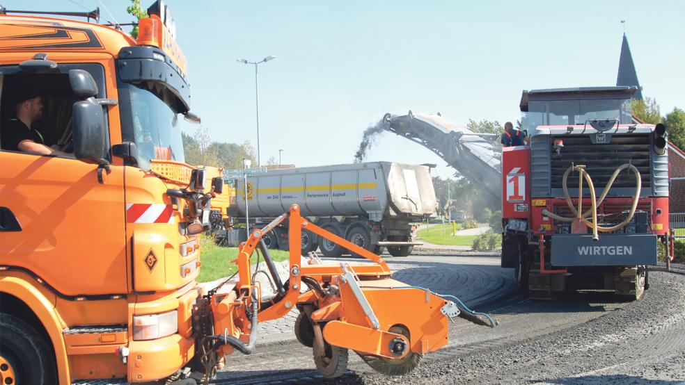»Kreisverkehr« gestern im Kreisel in Möhlenwarf: Der Asphalt der Fahrbahn wird gerade abgefräst, die Bruchstücke landen direkt in einem Lastwagen, direkt dahinter fährt ein weiterer Lastwagen, der die Fahrbahn reinigt.  © Foto: Hoegen