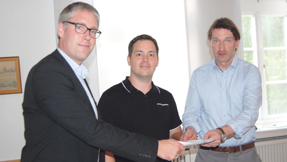 Bürgermeister Heiko Abbas und Günter Geerdes (rechts) nahmen im Rathaussaal die Unterschriftenliste aus der Hand von Hartmut Timmer entgegen.  © Foto: Hoegen