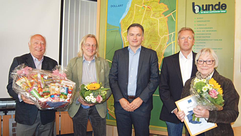 Der große Präsentkorb, den Kurt Kunert (links) von der Bezirksvereinigung Deutscher Schiedsmänner und Schiedsfrauen hier festhält, gehört Ina Penon (rechts), sie war zehn Jahre lang Schiedsfrau in Bunde. Neben Kunert der neue Schiedsmann Jelko Peters, Bürgermeister Uwe Sap und Richter Heiko Brahms vom Amtsgericht Leer.  © Foto: Hoegen