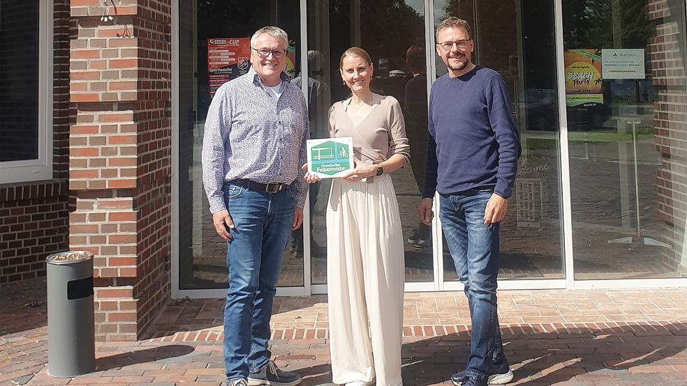 Kurt Radtke (Deutsche Fehnroute), Kerstin Freudenberg (Hotel »Preyt«) und Uwe Reiners (Touristinformation Hesel) bei der Übergabe des Plexiglasschildes mit dem Logo der Deutschen Fehnroute.  © Foto: Fehnroute