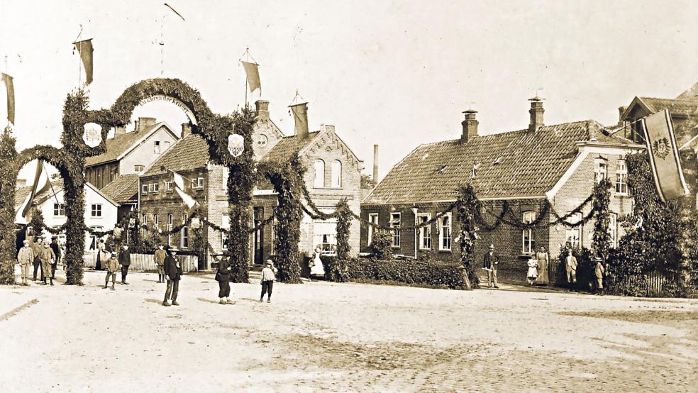 Sedanfeier 1898: Vor dem Haus des Fleischhändlers Jakob Hammerschlag an der Bahnhofstraße 2 (hinter dem großen Bogen) in Weener ist feierlich geschmückt worden. Heute steht dort kein Gebäude mehr. Aber ein Stolperstein soll an die jüdische Familie erinnern.  © Foto: Archiv Insel Lönig