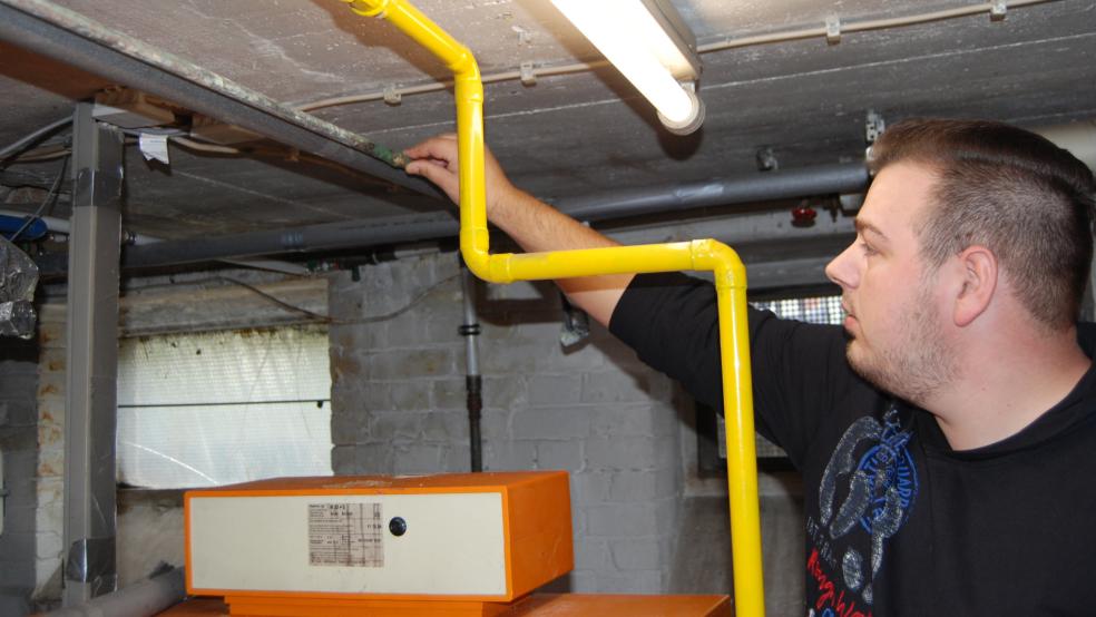 Jeremy Karen, der mit seiner Frau und drei Kindern in dem Wohnblock an der Friesenstraße 20 lebt, zeigt an einem der Rohre der Heizungsanlage, dass hier schon geflickt wurde. Jetzt ist die Heizung endgültig ausgefallen. © Hoegen