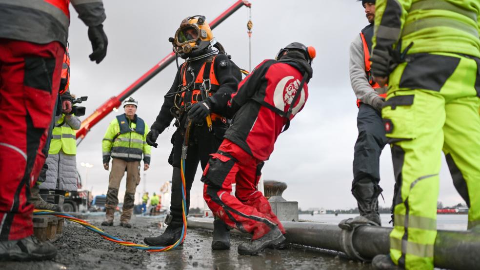 Taucher bereiten sich auf die Bergung des gesunkenen Frachters aus dem Hafenbecken vor.  © Penning (dpa)