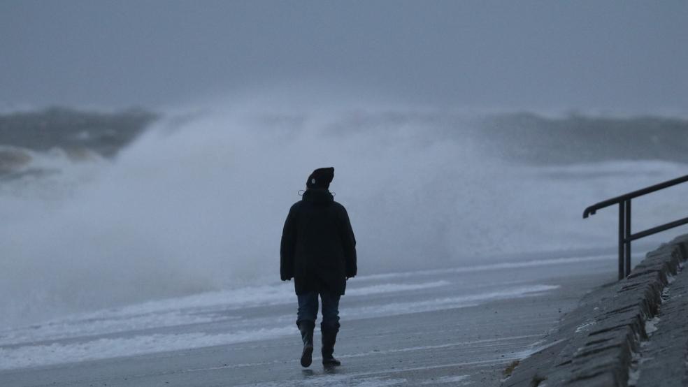 Eine Spaziergängerin läuft bei stürmischem Wetter am Nordstrand der ostfriesischen Insel Norderney.  © dpa/Volker Bartels