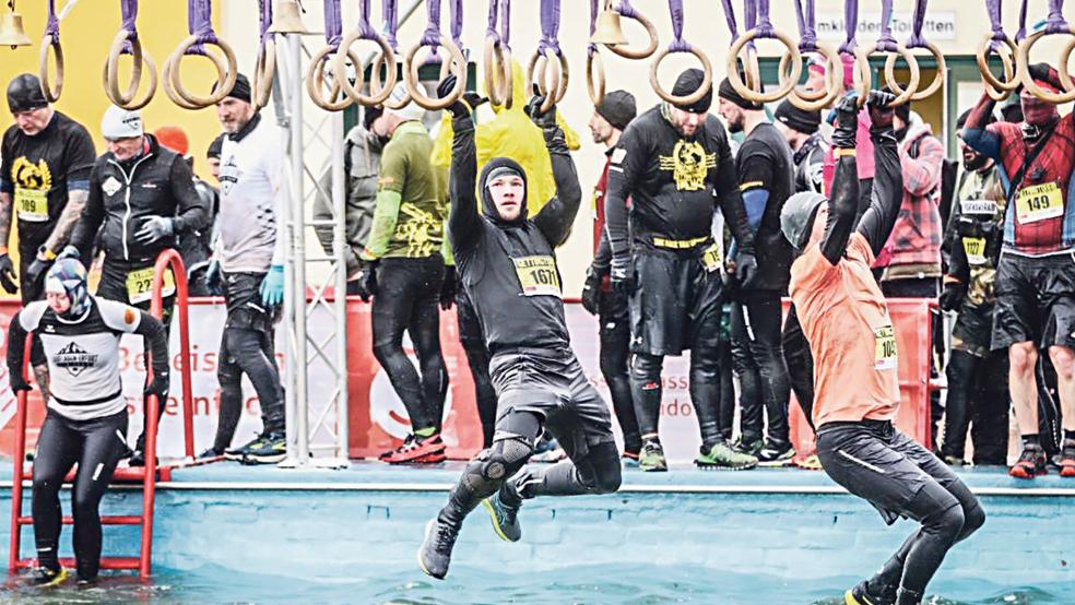 Henning Kruse (Bildmitte) hangelt sich an Greifringen über das eiskalte Freibad.  © Foto: privat