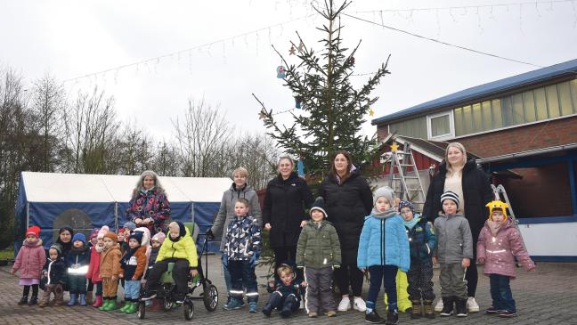 Kinder schmücken Tanne für Weihnachtsmarkt