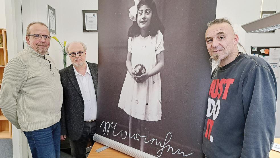 Mit einem Poster, das die 1927 in Riepe geborene und 1944 im KZ Ravensbrück gestorbene Mariechen Franz zeigt: Ingo Lindemann (links) und Stefan Wagner (rechts) vom Sinti-Verein Ostfriesland stellten zusammen mit dem Historiker Dr. Hans Hesse das Gedenk-Projekt vor.  © Foto: Szyska