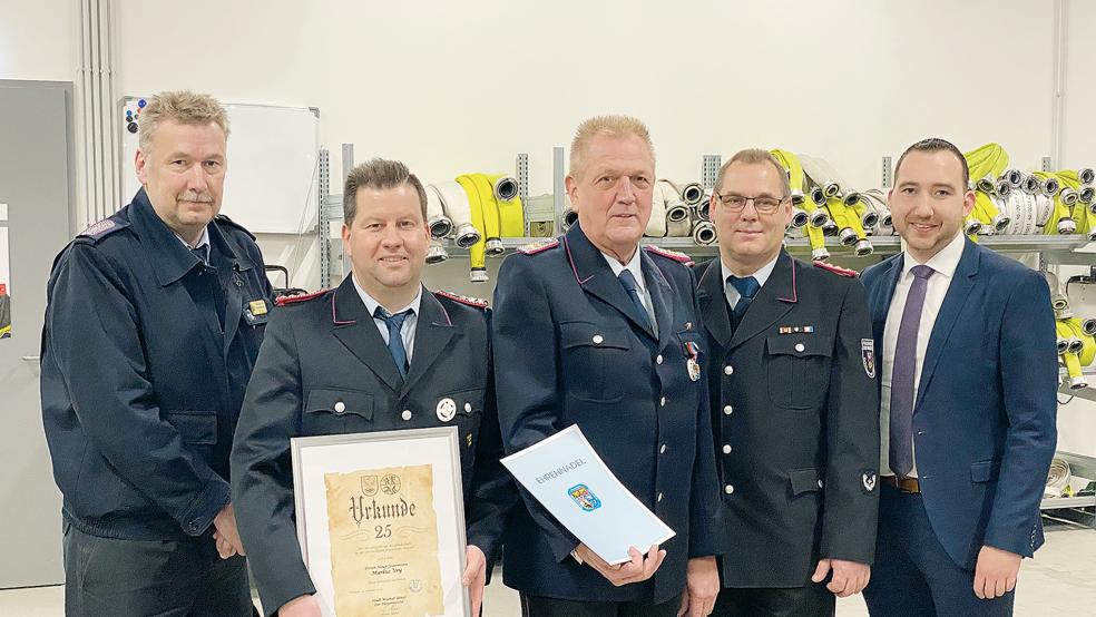 Die Feuerwehrmänner Markus Vry (vorne links) und Helmut Erfkamp erhielten eine Urkunde zum Jubiläum beziehungsweise für besondere Verdienste, überreicht von Ernst Berends (links), Stadtbrandmeister Jörg Fisser und Nico Bloem (rechts) als Stellvertreter des Bürgermeisters.  © Foto: Kuper